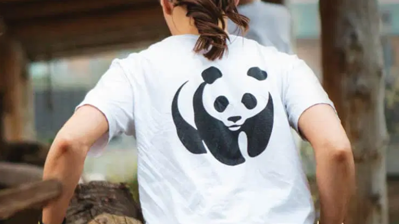 Ragazza vista di spalle mentre trasporta una cariola. Si vede la maglietta con il logo del wwf: un panda stilizzato in bianco e nero.